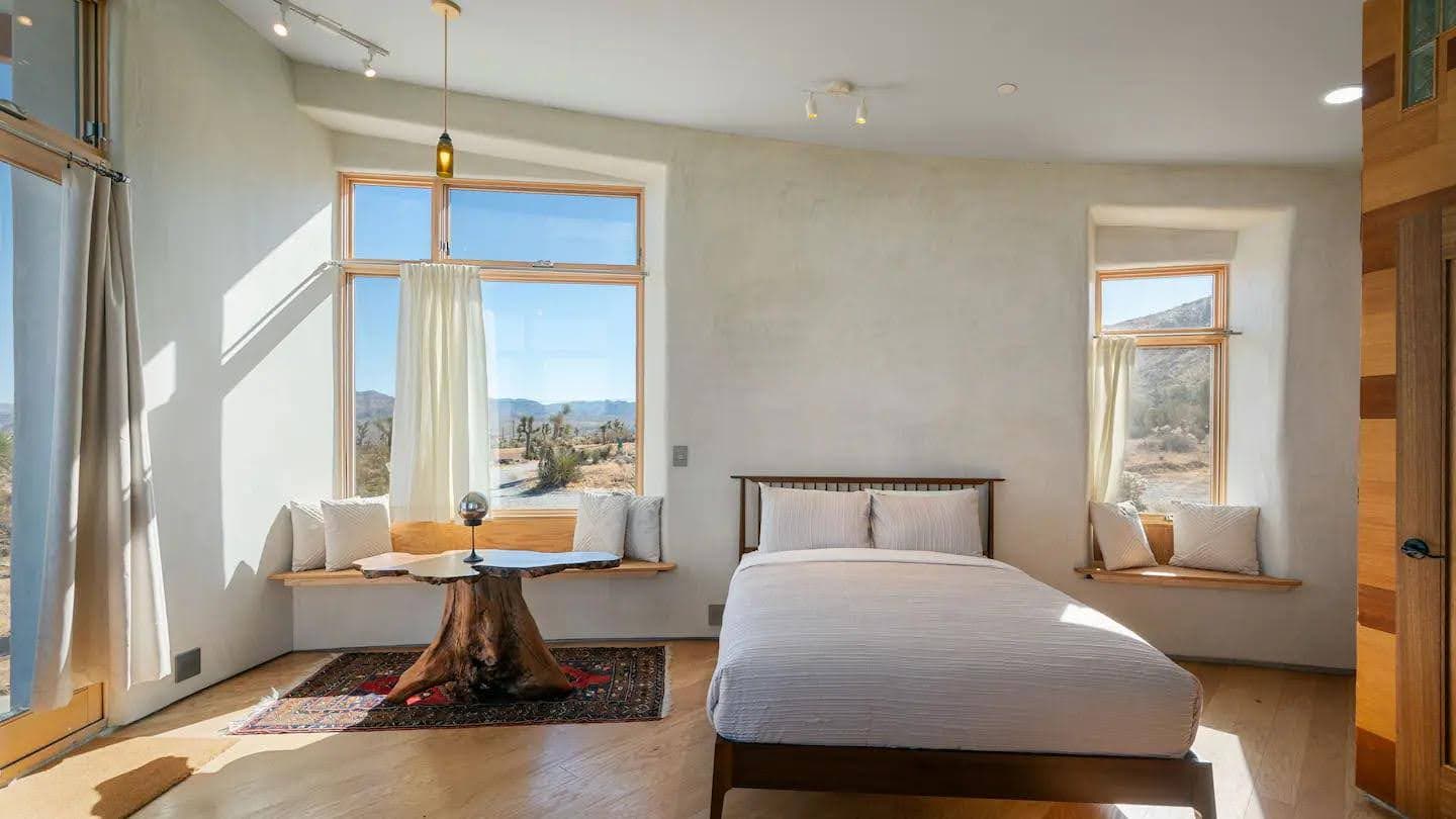A daylight bedroom interior at Mesa Sky Disk with a desert view through large windows.