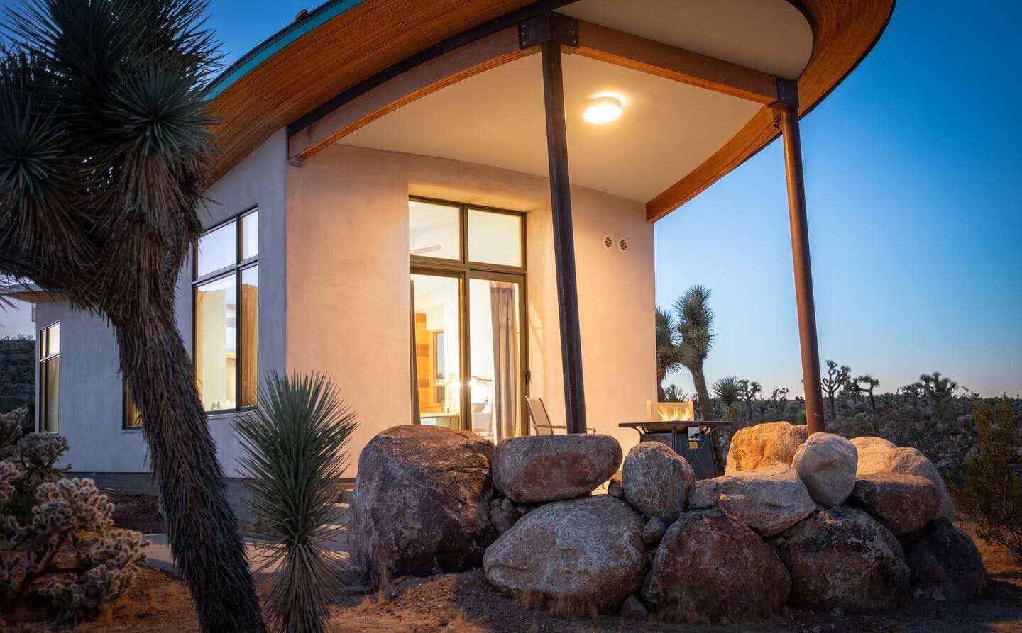 Fire table and seating beneath the curved roof at Mesa Sky Disk, dusk.